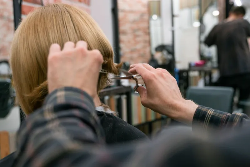 Frisør klipper en kundes hår i en travl salon