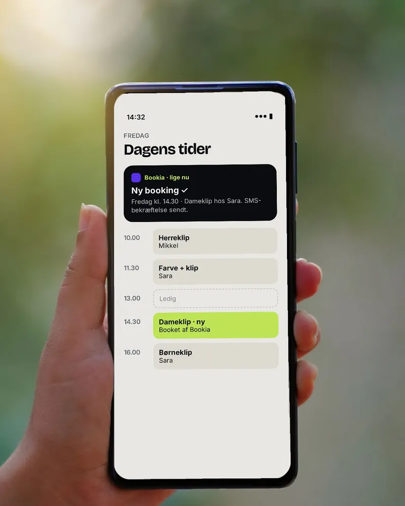 Hånd holder en telefon med en dagskalender, hvor en ny booking er lagt ind (illustration)